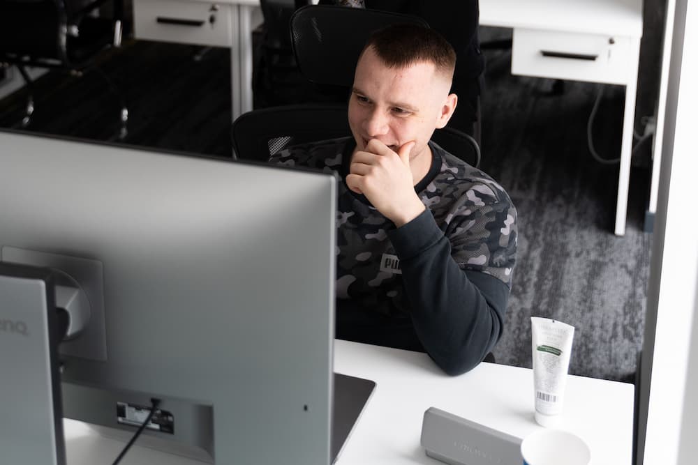 Serhii Shramko is sitting at a table on front of a computer and coding